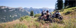 cyclists at the top of a trail with rocky mountains in background