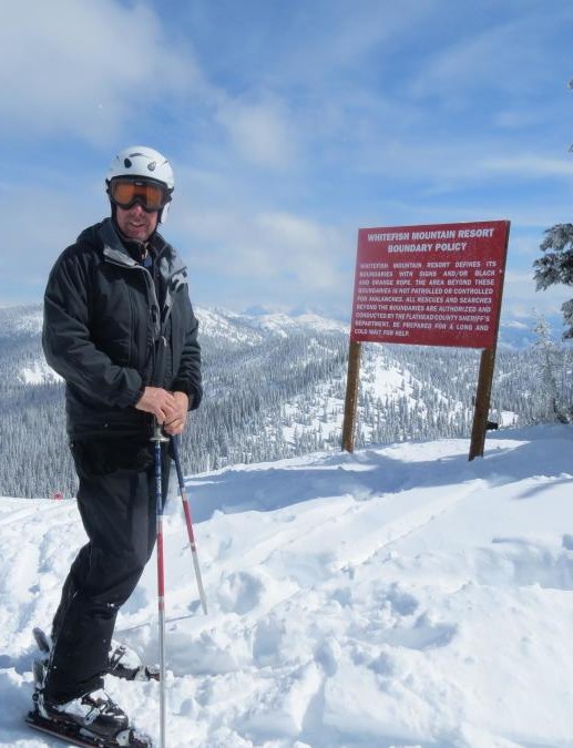 joe brenneman in ski attire stands at the top of a snowy trail