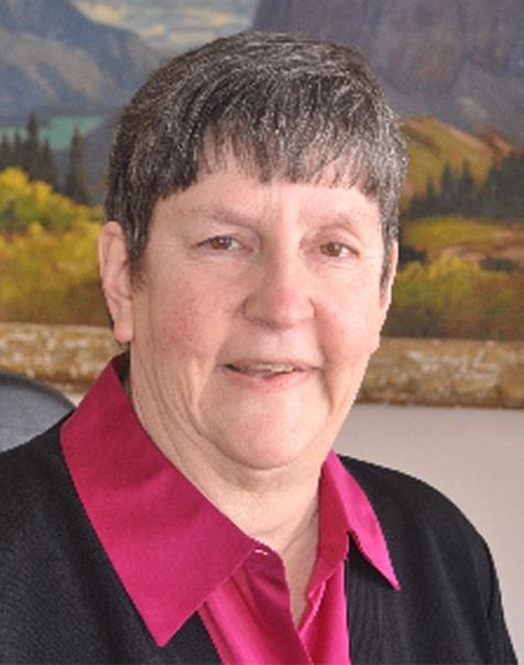 Jane Lopp smiling at the camera wearing a pink collared shirt