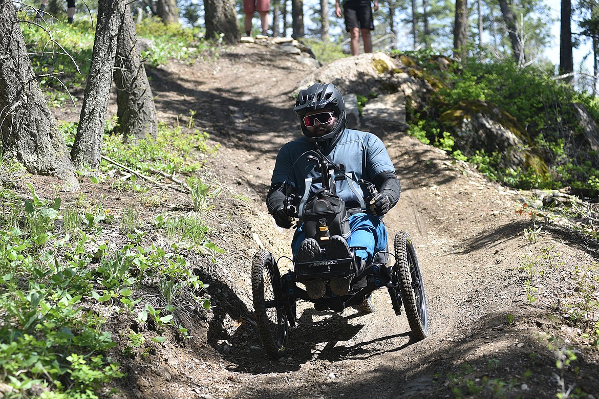 An adaptive bike and rider are going down a steep trail